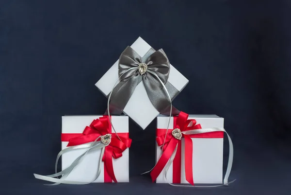 多くの贈り物 ギフトボックスは赤とグレーの美しい弓で白いです 暗い背景に贈り物 休日や驚き サテン弓とともにラインストーン — ストック写真