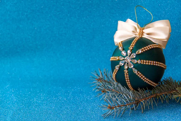 Mavi arka planda Noel ağacı süslemesi için Noel balosu. Spruce dalı ve yapay elmaslı Noel balosu.