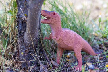 Çalılıktaki oyuncak dinozor doğal çevreyi taklit eder. Çocuklar için oyuncaklar.