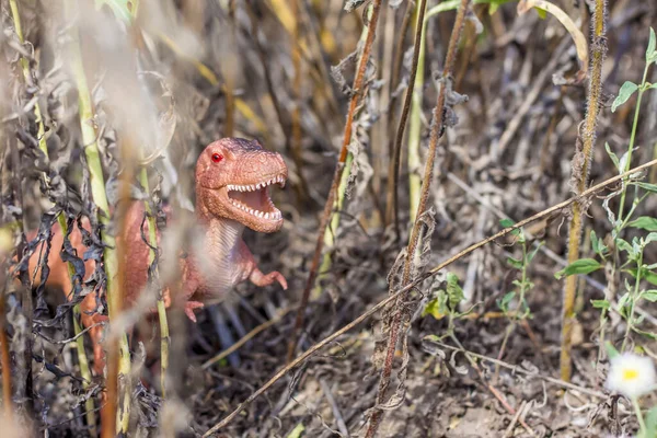 Toy dinosaur in the thicket imitates the natural environment. Toy for children.