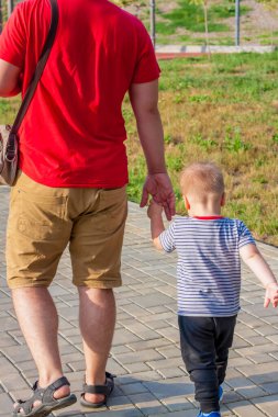 Baba ve oğul el ele yürür. Bir adam bir çocuğu elinden tutar..