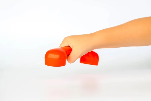 Red toy phone in the child's hand. Close-up of a child's hand. Isolated on a white background. The concept of an advertising banner. Emergency call. Phone call. Hand holding a green phone.