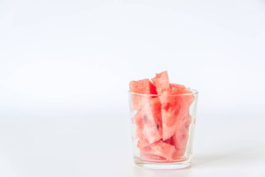 Olgun kırmızı karpuz, taramada beyaz arka planda parçalara ayrılmış. Bardakta karpuz dilimleri. Beyaz arkaplan. 