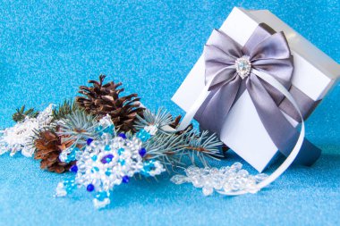 Hediye kutusu, ladin dalı ve parlak bir arka planda köknar konisi. Pullu mavi arkaplan. 