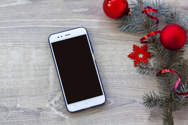 İnternetten Noel hediyesi al. İnternetten alışveriş. Yeni yıl. Çevrimiçi mağazalar, indirimler ve hediye konseptleri. Bir dal ladin ve bir akıllı telefon ile süslenmiş. Noel ya da yeni yıl alışverişi konsepti. 