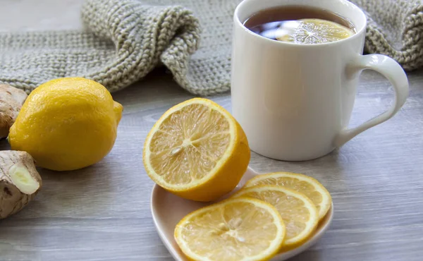 Ginger tea with lemon. Season of colds and infections. Strengthening of immunity. A Cup of tea with lemon and ginger in a warm scarf.