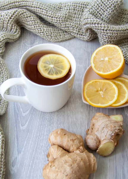 Ginger tea with lemon. Season of colds and infections. Strengthening of immunity. A Cup of tea with lemon and ginger in a warm scarf.