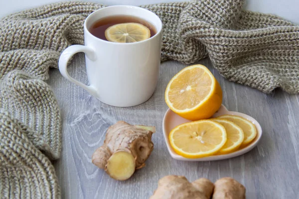 Ginger tea with lemon. Season of colds and infections. Strengthening of immunity. A Cup of tea with lemon and ginger in a warm scarf