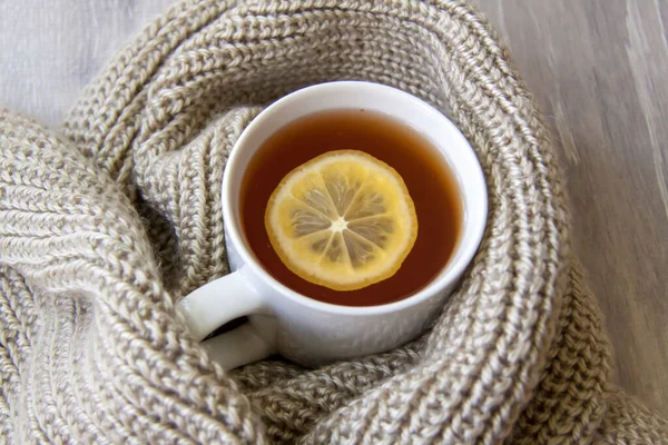 Ginger tea with lemon. Season of colds and infections. Strengthening of immunity. A Cup of tea with lemon and ginger in a warm scarf.