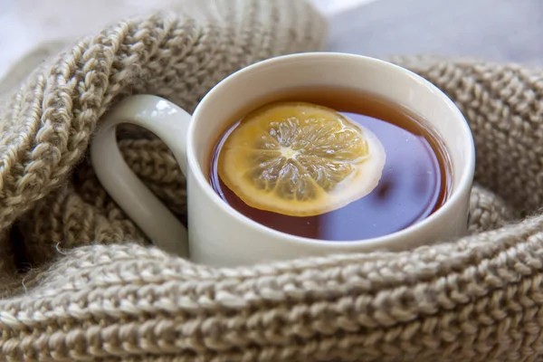 Limonlu zencefil çayı. Soğuk algınlığı ve enfeksiyon mevsimi. Bağışıklığın güçlenmesi. Sıcak bir eşarpla limonlu ve zencefilli bir fincan çay..