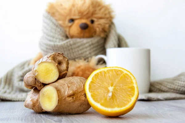 Limonlu zencefil çayı. Soğuk algınlığı ve enfeksiyon mevsimi. Bağışıklığın güçlenmesi. Sıcak eşarplı oyuncak ayının arka planında limonlu bir fincan çay..   