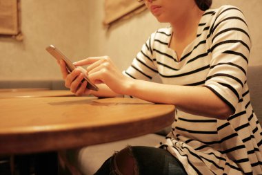 cep telefonu kullaranarak ve rahat restoran arka plan kopya alanı ile bekleyen genç kadın