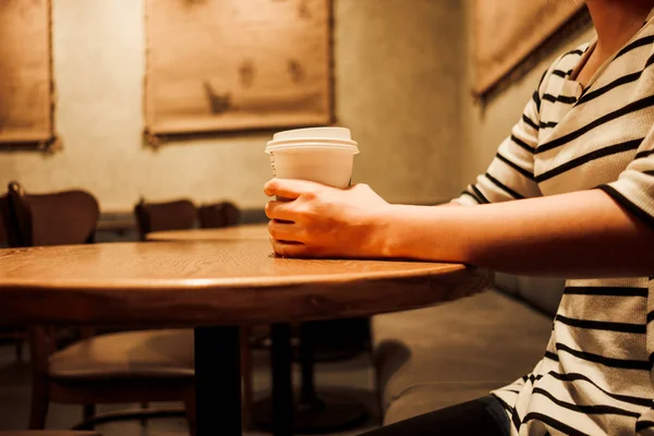 lifestyle background young woman holding coffee glass sitting alone in restaurant with copy space. image for food, person, beverage, portrait concept