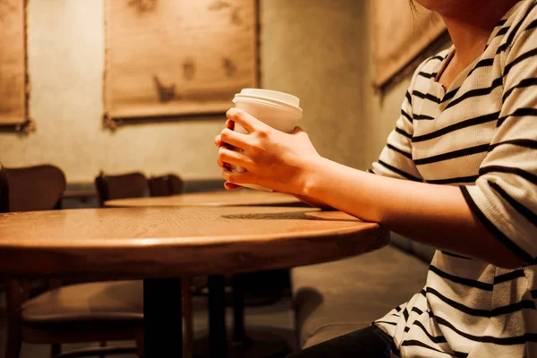 lifestyle background young woman holding coffee glass sitting alone in restaurant with copy space. image for food, person, beverage, portrait concept