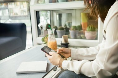 Tablo arka plan üzerinde çalışma alanı'nda oturan ve cep telefonuyla genç işkadını defter ve içecek vardır