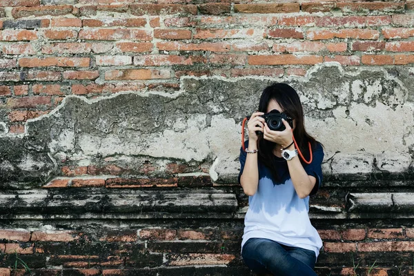 正面の肖像若い女性写真家カメラと古い寺院の壁の背景で写真を撮影 — ストック写真