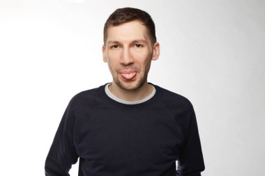 Portre yakışıklı esmer saçlı ve hoş bir görünüm, genç erkek gösterir dil, eğlenceli, bir arkadaş kandırmaya devam giyen koyu mavi rahat kazak, vardır. Sağlık, güzellik ve gençlik kavramı.