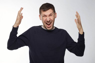 Öfkeli hareketle elele kızgın kızgın delikanlı izole portresi kapatın. Koyu renk gözleri mavi ceketli olan genç bir erkek. Negatif insan doğası, duygular, yüz ifadeleri, kavram duygu.