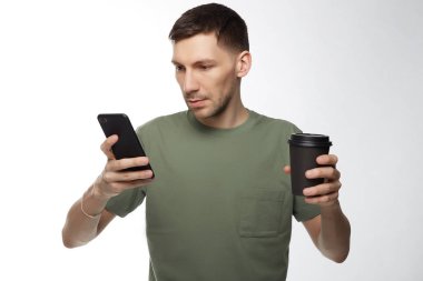 Düşünceli ciddi esmer erkek girişimci haki tişört, zor işten sonra kahve molası var, iş raporu modern dijital telefon, ücretsiz internet bağlantısı, telefon bekler ortağından yapar.