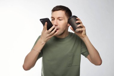Stüdyo çok çalışan genç Avrupa erkek girişimci telefon fincan kahve ile karışık doz izole. Yorgun Yöneticisi Mobil telefondan içip konuşmak içecek bir fincan götürün.