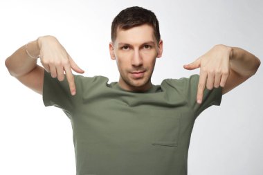 T-shirt tasarım ve reklam kavramı. Kapalı kopya alanı için senin bilgi ile boş onun üst aşağı parmakları işaret, bir şey yasak gösterilen moda Kafkas genç erkek portresi.