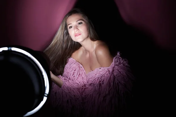 High fashion model woman in colorful bright lights over dark pink background. Close up portrait of beautiful Caucasian lady wearing trendy make-up and funky shaggy coat. Art design, colorful wall.