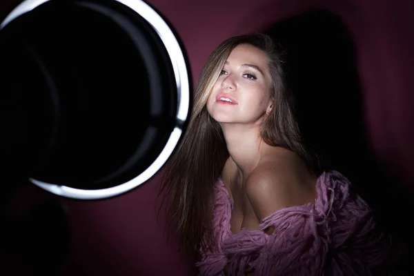 High fashion model woman in colorful bright lights over dark pink background. Close up portrait of beautiful Caucasian lady wearing trendy make-up and funky shaggy coat. Art design, colorful wall.