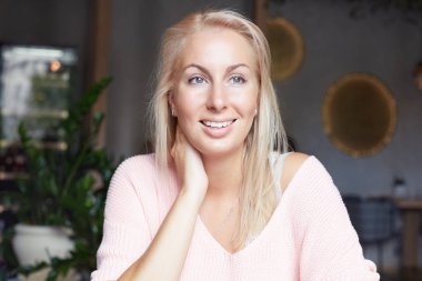 Memnun düşünceli sarışın kadın model casual giyim, rüya gibi bir ifadeyle yana doğru görünüyor, bir şey hoş, rahat hakkında düşünüyor, kafede boş zaman harcıyor. Yaşam tarzı kavramı.