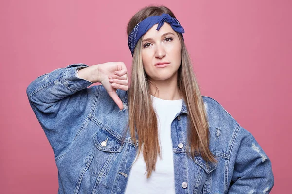 Moda erkek antipati vücut dili ile ifade eder, başparmak aşağı tutar ve yüz frowns, memnun yüz, denim stil, eğriler dudaklar, pembe arka plan üzerinde izole. Bu gerçekten kötü bir fikirdir!