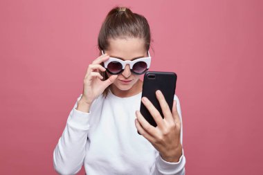 Şok şık beyaz hipster Bayan haber online okur, modern cep telefonundan ücretsiz internet bağlantısı kullanır, erkek arkadaşı hakkında dedikodu şok edici dışarı bulur. Şaşırmış gibi kadın modeli almak tuhaf mesaj