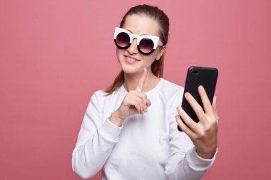 Güzel genç kadın uzun saç modeli vardır, akıllı telefon ve kulaklık üzerinden görüntülü görüşme yapar, online arkadaşıyla konuşuyor, at gülümsüyor kamera olumlu, bekle bir dakika sorar, o daha sonra arayacağım.
