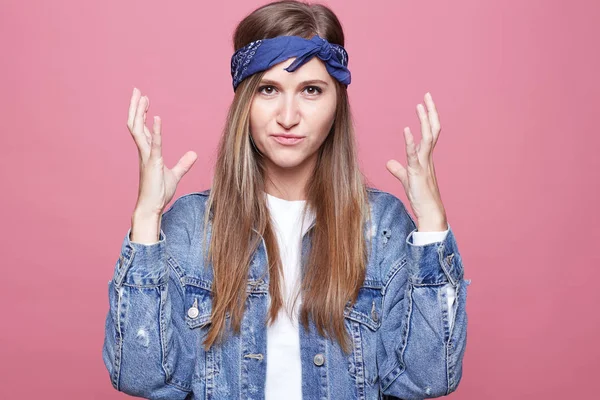 Kızgın hipster kadın kahverengi düz uzun saçlı şüpheci ve memnun ifade ile silah kaldırdı kameraya bakıyor. Güzel kadın serbest meslek hayal kırıklığına, iletişim ile kızgın portresi.