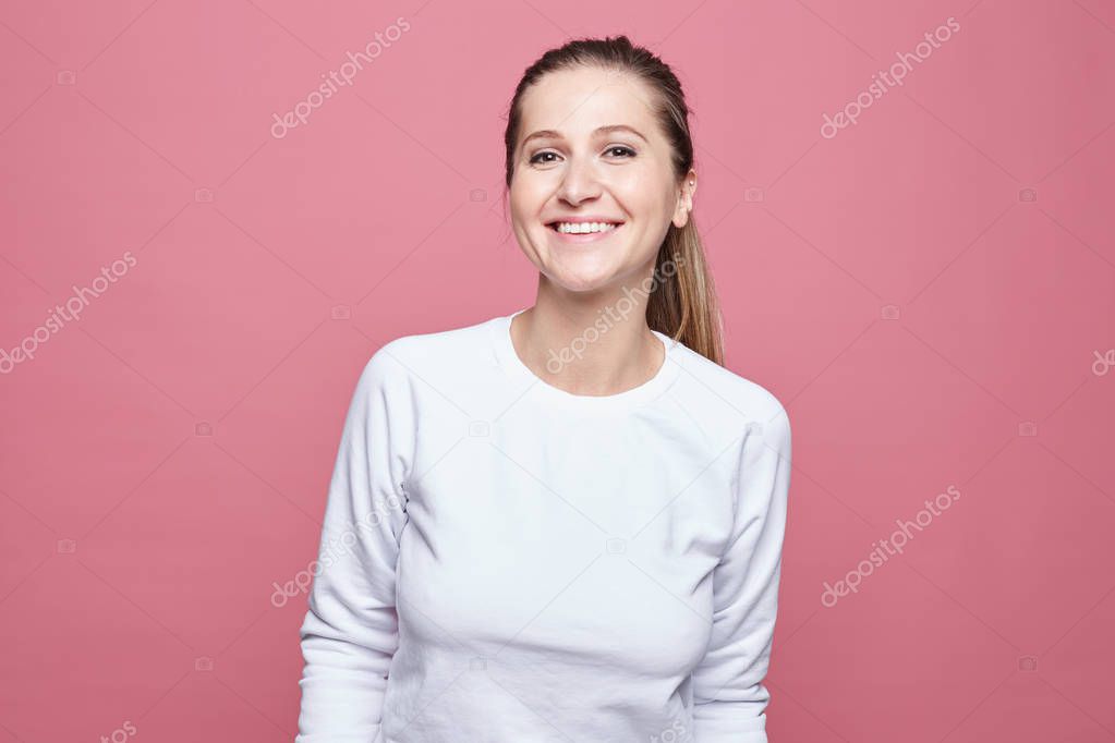 Happy woman laughing. Closeup portrait of woman with perfect smile and white teeth, looking happy, isolated over pink wall background. Positive human emotion, facial expression, body language conept.