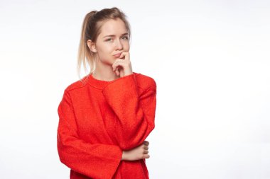 Genç kadın adil sarı saçlı ve yeşil gözlü çatık kaşları işaret parmağı çene şüphe ve bir şey hakkında şüphe hissi şüpheci olması üzerinde tutarak. İnsan duygu ve ifadeler kavramı.