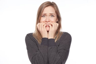 Çivi, ısırma korkmuş hayran genç sarışın kadın ile uzun düz saç, kamera, dehşete ifade ile görünüyor portresi sinir, beyaz stüdyo duvar karşı izole olmak. İnsan duyguları kavramı.