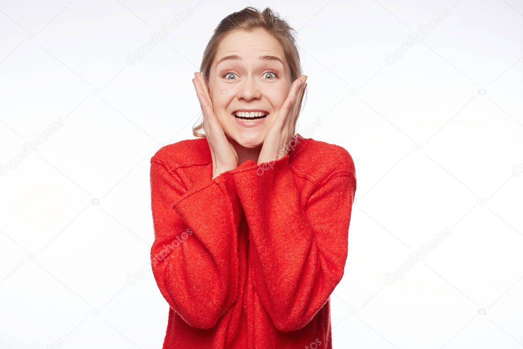 Portrait of excited female model has appealing appearance stares at camera with unbelievable gaze, surprised to receive unexpected gift from relatives. People, facial expressions, emotions concept.