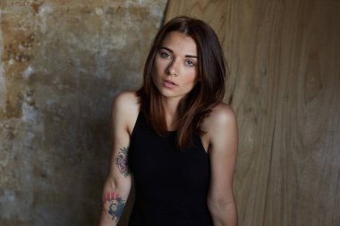 Güzellik ve insan. Ahşap duvar karşı ciddi ve dalgın ifade ile kameraya bakarak doğal karışık yarış kartlarının ihale olan kadın şık saç kesimi ve karanlık şehvetli, otantik çekim.