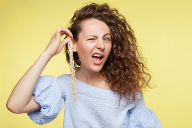 Yapması ve palyaçoluk, üstte olmak genç kadın mavi gözleri ve mizah, büyük anlam ile samimi portresi. Güzel erkek sarı stüdyo duvarda izole kapalı, eğleniyor erişte ile oynuyor.