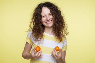 Sevimli genç güzel kadın tatlı kırmızı domates, onları koyarak göğsüne, yeni form meme, estetik ameliyat yapacak hayal tutar. Kadın doğal vücut teşvik güzel dişlek gülümseme ile.