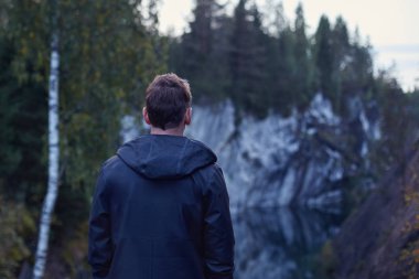Seçici odak doğal mermer duvarlar hayran yağmur ceket adam, arkasında. Otantik Kuzey doğa güzellikleri çevresindeki derin ormandaki ağaçlar su yansıması ile Kanyon düşünürken erkek vurdu.