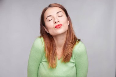 Güzel bayanı yuvarlak dudaklar ve kapa gözlerini, öp yapar, uzun siyah saçlı, gri bir arka plana dayanır memnun, pozlar, onun olumlu duygu ifade eder, keyifli tutum hayal.