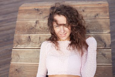 Atış iyi görünümlü Avrupa Genç kadının zarif pembe bluz giymiş kıvırcık saç kesimi ile yakından iskelede boş zaman harcıyor, gençlik, sahiptir yaz, aşk hakkında rüyalar. Açık hava yaşam tarzı kavramı. 