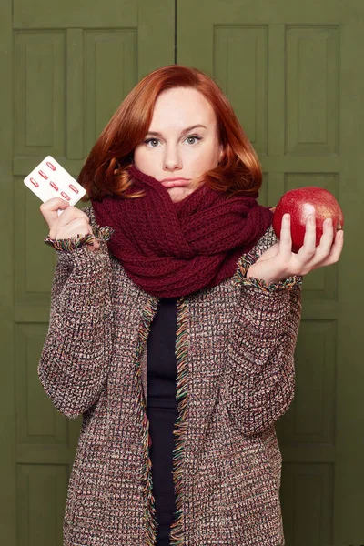 Amused attractive Caucasian female with outstanding ginger bob hairstyle curving lips in misunderstanding, not knowing how to stay healthy during winter time period, posing on green door background.