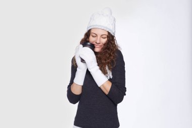 Rahat peri kış kez geliyor. Yeni oldukça beyaz kadın zevk dış giyim, duygu rahat ve şanslı, sıcak içecek ile siyah Kupası holding, gülümseyen ve beyaz reklam için poz.