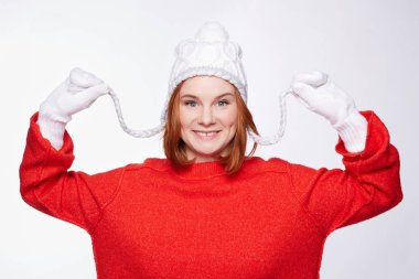 Beyaz örme eldiven ve şapka ile iki bezleri, kamera geniş mükemmel dişlek gülümseme ile seyir giyen neşeli Amerikan çilli olan kadın zencefil bob saç modeli, stüdyo çekim kapatın. 