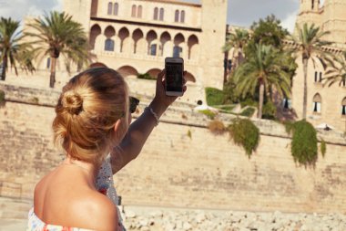 Seçici odak üstünde telefon. Sarışın kadın selfie kız arkadaşı ile yapma geri vurdu. Çıplak omuz ile yaz elbiseli kadın resim üzerinde Antik kentin artalanları alır. Seyahat ve kavramı keşfetmek