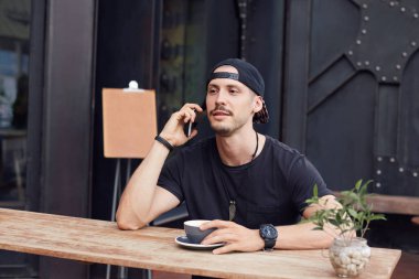 İnsanlar, modern yaşam, teknoloji ve iletişim kavramı. Öğle yemeği sırasında arkadaşıyla telefon konuşma yaparken kupa dışında çay veya kahve içme çekici beyaz adamın samimi atış.