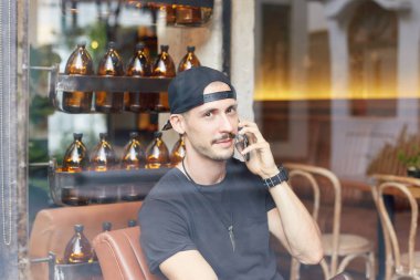 Yavaşça kameraya üstünde hareket eden telefon, konuşurken oynak göz, muhatap için dikkatle dinliyor olması gülümseyen yakışıklı sevindim beyaz adamın sakal ve bıyık, camdan resim. 