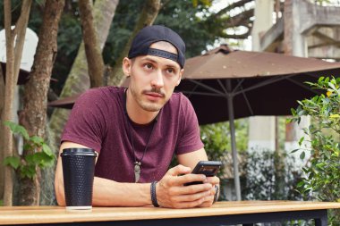 Dalga köpüğü enterne içinde ücretsiz wifi üzerinden cep telefonu, modern kafede kahve molası sırasında oturan gündelik kıyafeti giymiş genç yakışıklı erkek olmanın başka bir adamla yürüyüş arkadaşı görmek sürpriz