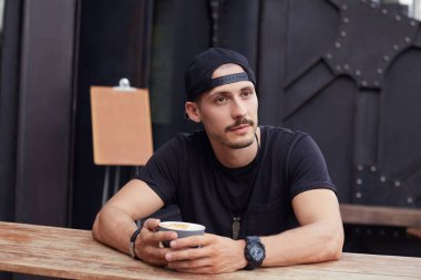 İnsanlar, yaşam kavramı. Kahve molası sanat projesi, bittikten sonra dinlenirken yana doğru seyir zevk freelancer siyah t-shirt ve şapka, yakışıklı kendine güvenen genç beyaz sakallı.